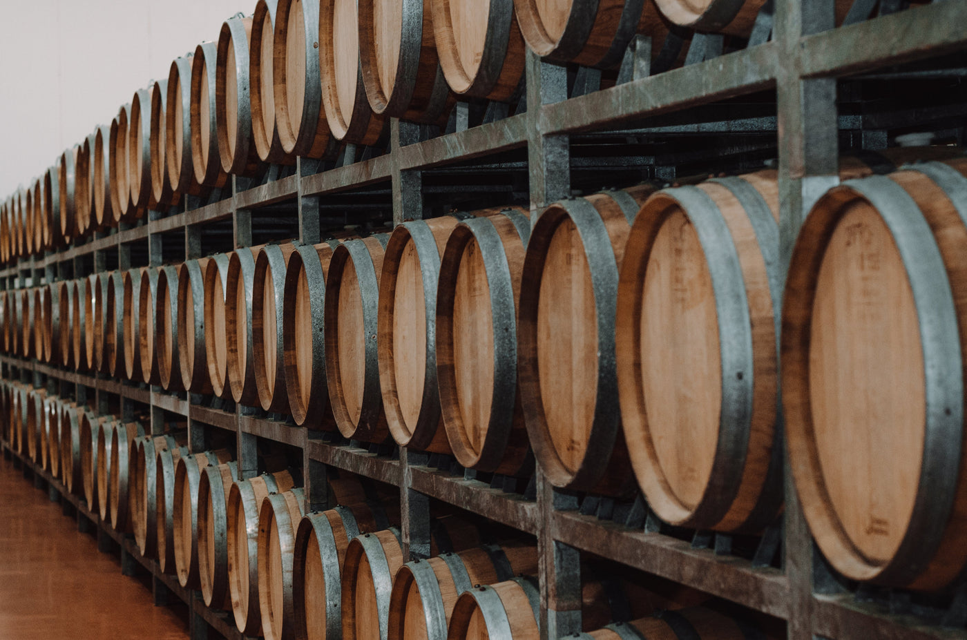 Row of wooden wine barrels on metal racks at Bodega Dos Hemisferios